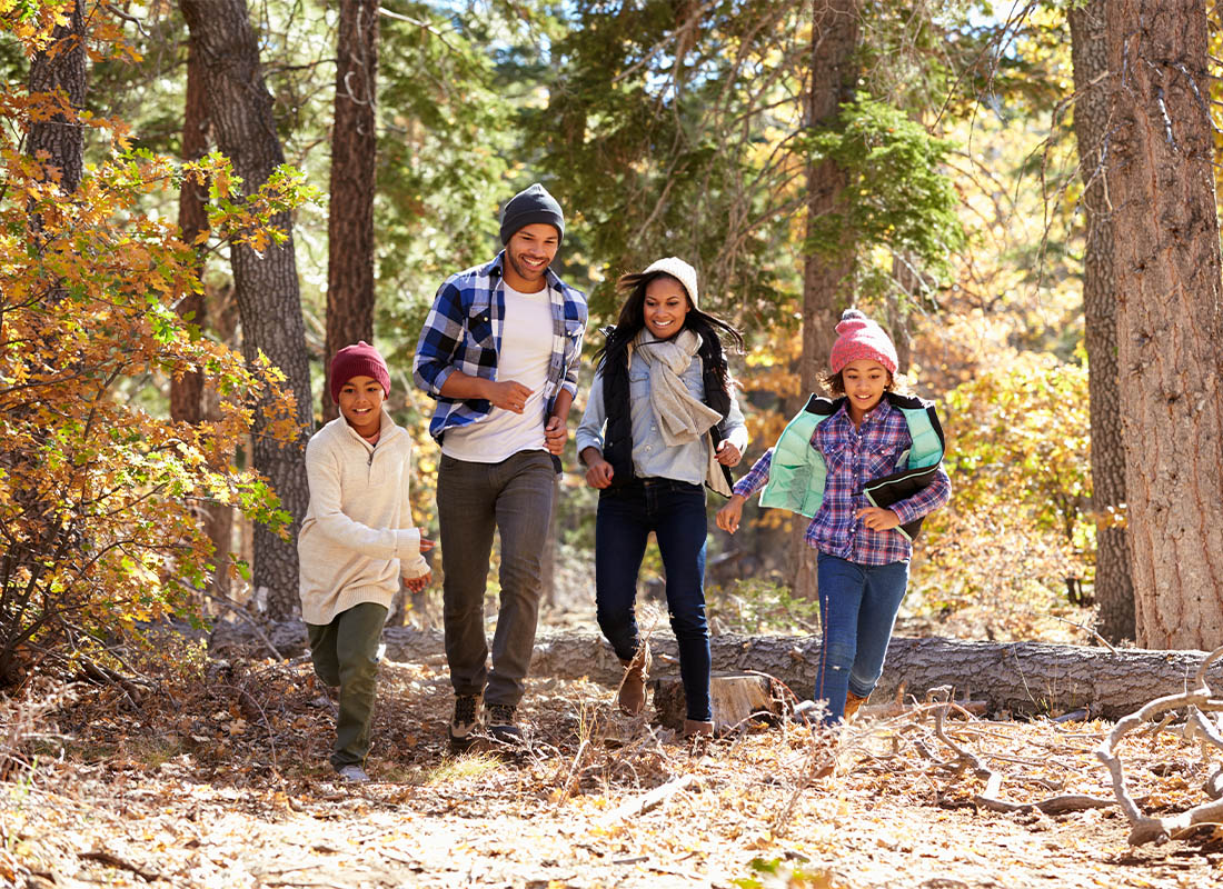 Personal Insurance - A Smiling Family Having Fun and Hiking in the Woods During the Fall